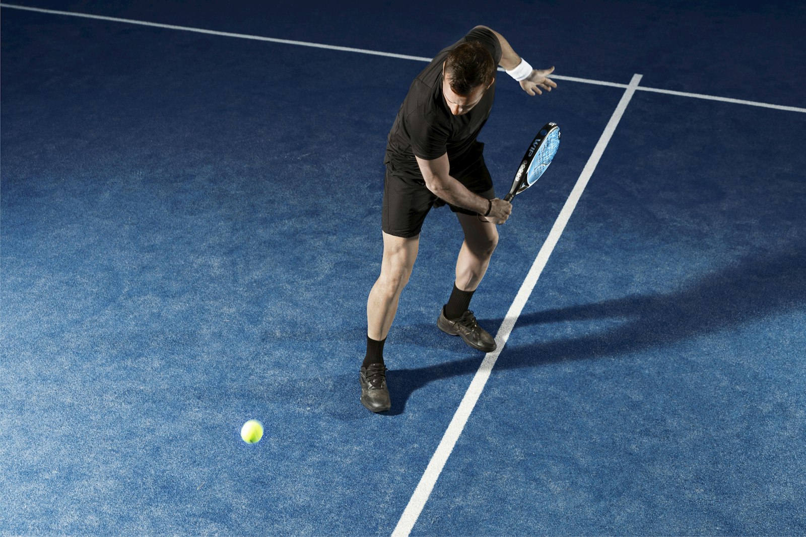 A padel player mid-swing on court
